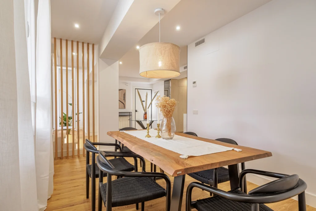 Comedor con mesa de madera maciza, sillas negras y lámpara de fibra del ático de Francisca Moreno 3, Madrid