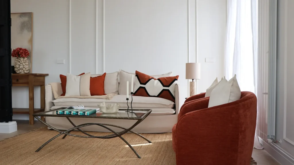 Salón del piso en venta en Menéndez Pelayo 47, Madrid, con sofá, butaca terracota y paredes con molduras