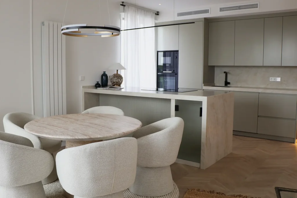Comedor con mesa redonda y cocina abierta con isla en el piso de Menéndez Pelayo 47, barrio de Salamanca