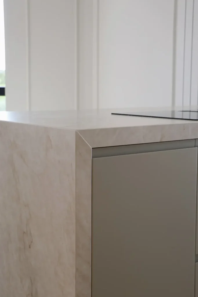 Detalle de la encimera veteada con lateral en cascada y frente de armario verde salvia de la isla de cocina
