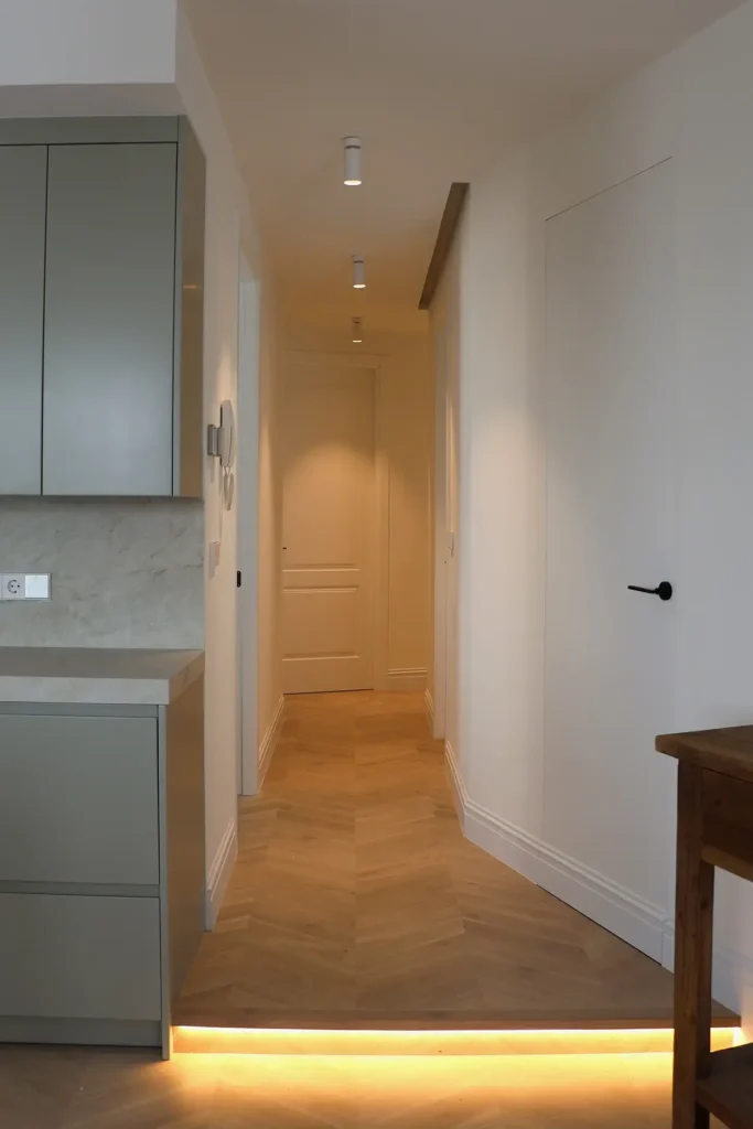 Pasillo desde la cocina con parquet en espiga, focos en el techo y tira de luz LED en el suelo